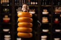 Handsome cheese sommelier with yellow wheels of cheese in shop. Worker of food cheese store carrying rounds of cheese.