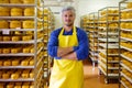 Handsome cheesemaker is checking cheeses in his workshop storage.