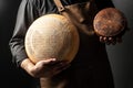 Handsome cheesemaker is checking cheeses in his workshop storage, close up Royalty Free Stock Photo