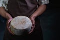 Handsome cheesemaker is checking cheeses in his workshop storage. Royalty Free Stock Photo