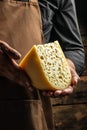 Handsome cheesemaker is checking cheeses in his workshop storage, close up Royalty Free Stock Photo