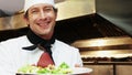 Handsome chef holding a plate with a poach pear