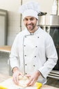 Handsome chef smiling and kneading dough on Royalty Free Stock Photo