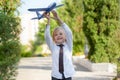 Handsome child boy with toothless smile in white shirt plays with toy airplane on outdoors