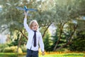 Handsome child boy with toothless smile in white shirt plays with toy airplane on outdoors