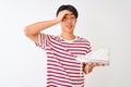 Handsome chinese man holding casual sneakers standing over isolated white background stressed with hand on head, shocked with Royalty Free Stock Photo