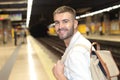 Handsome commuter smiling while waiting for his train Royalty Free Stock Photo