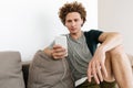 Handsome concentrated man sitting at sofa using mobile phone