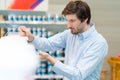 handsome concentrated young man choosing paints in hardware store Royalty Free Stock Photo