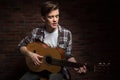 Handsome concentrated young man playing acoustic guitar and singing