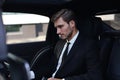 Handsome confident businessman in suit talking on smart phone and working using laptop while sitting in the car Royalty Free Stock Photo