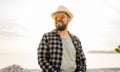 Handsome and confident. Outdoor portrait of smiling millennial man wearing hat and sunglasses on beach. Holidays travel Royalty Free Stock Photo