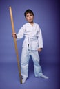 Handsome confident child boy in white kimono with wooden weapon bokken over purple background with copy space. Oriental martial Royalty Free Stock Photo