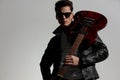 handsome cool man wearing leather jacket and holding guitar on shoulder Royalty Free Stock Photo