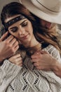 Handsome cowboy man in white hat touching cheek of beautiful boho gypsy woman with leather headband, face closeup portrait Royalty Free Stock Photo