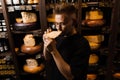 Handsome customer in cheese shop sniff and enjoy limited gouda cheese. Snack tasty piece of cheese for appetizer.