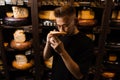 Handsome customer in cheese shop sniff and enjoy limited gouda cheese. Snack tasty piece of cheese for appetizer.