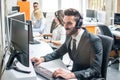 Handsome customer support agent with headset working on computer in call center. Royalty Free Stock Photo