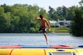 Handsome cute boy jumping at a water trampoline floating in a lake in Michigan during summer. Royalty Free Stock Photo