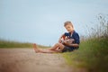 Handsome cute boy is playing on acoustic guitar sittingon road in summer day. Royalty Free Stock Photo