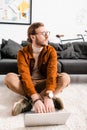 3d artist looking away while using laptop on floor in office