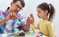 Handsome dad and cute daughter study biology and chemistry lesson with microscope. Little girl with father doing science Royalty Free Stock Photo