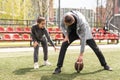 Handsome dad with his little cute daughter are having fun and playing American football on green grassy lawn Royalty Free Stock Photo