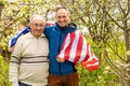 Handsome dad with his little cute sun are laying on green grassy lawn on American flag with American football ball in Royalty Free Stock Photo