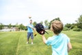 Handsome dad with his little cute sun are playing baseball on green grassy lawn Royalty Free Stock Photo