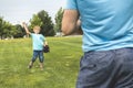 Handsome dad with his little cute sun are playing baseball on green grassy lawn Royalty Free Stock Photo