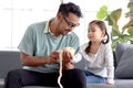 Handsome dad peeling apple for his daughter, cute little girl sitting on sofa in living room, waiting to eat apple, lovely family Royalty Free Stock Photo