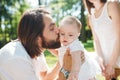 Handsome dark-haired father with beard is kissing his little charming daughter on a summer day in the park. Royalty Free Stock Photo