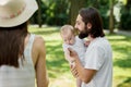Handsome dark-haired father is gently holding in the arms his little charming daughter on a summer day in the park. Royalty Free Stock Photo