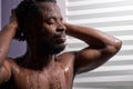 Handsome dark skineed man taking shower in bathroom Royalty Free Stock Photo