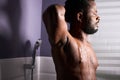 Handsome dark skineed man taking shower in bathroom Royalty Free Stock Photo