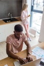 African man using laptop while caucasian girlfriend standing lonely at kitchen Royalty Free Stock Photo