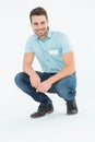 Handsome delivery man crouching on white background