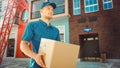 Handsome Delivery Man Holds Cardboard Box Package Walks Through Modern Stylish Business District. Royalty Free Stock Photo