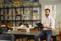 Handsome designer, architect seller sitting on table, writing.