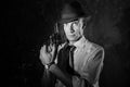 Handsome detective in hat holding a gun in the dark Royalty Free Stock Photo