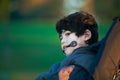 Handsome disabled boy in wheelchair at park, quiet expression