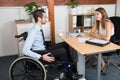 Handsome disabled businessman in a wheelchair at his office in front of a beautiful young woman