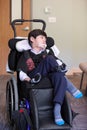 Handsome disabled eight year old biracial boy smiling and relaxing in wheelchair