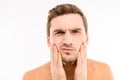 Handsome disturbed young man touching his face after shave Royalty Free Stock Photo