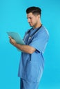 Handsome doctor with clipboard on background