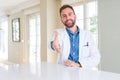 Handsome doctor man wearing medical coat at the clinic smiling friendly offering handshake as greeting and welcoming Royalty Free Stock Photo