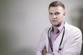 Handsome doctor with stethoscope and folded arms looking at camera Royalty Free Stock Photo