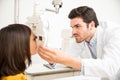 Attractive optician doing eye sight checkup for small girl at of