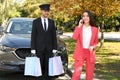 Handsome driver with shopping bags and young businesswoman near car