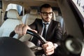 handsome driver in suit driving car and looking